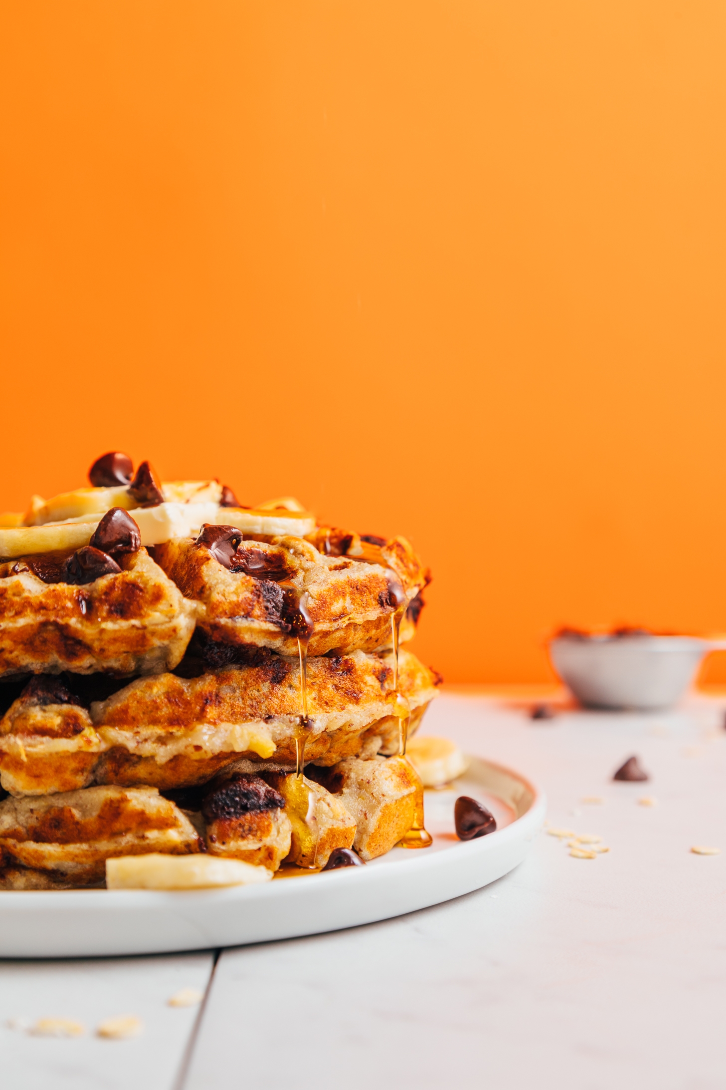 Maple syrup dripping off a stack of Chocolate Chip Banana Bread Waffles