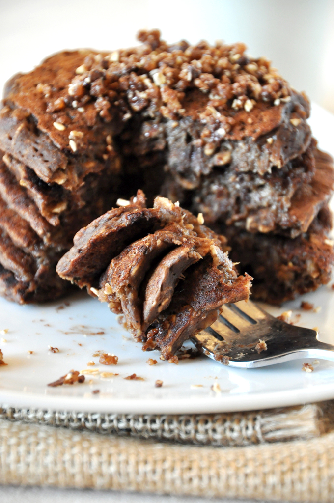 Pancakes that taste JUST LIKE a no bake cookie! Bite of vegan No-Bake Cookie Pancakes resting on a plate beside the rest of the stack