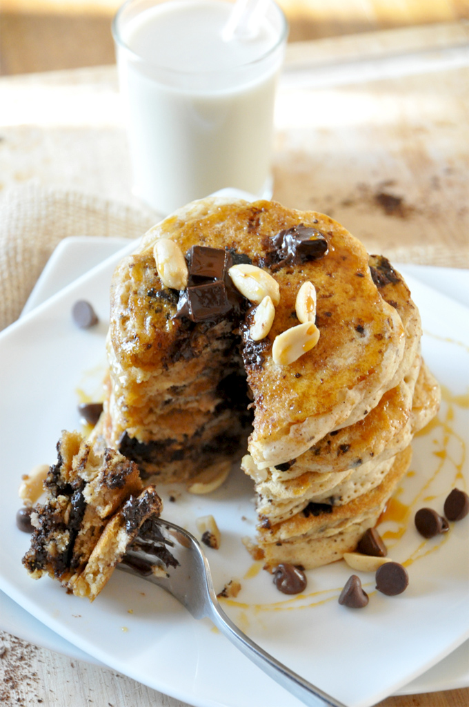 Bite of Vegan Snickers Pancakes resting on a fork next to the rest of the stack