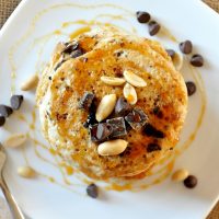 Top down shot of a stack of Snickers Pancakes topped with dark chocolate and peanuts