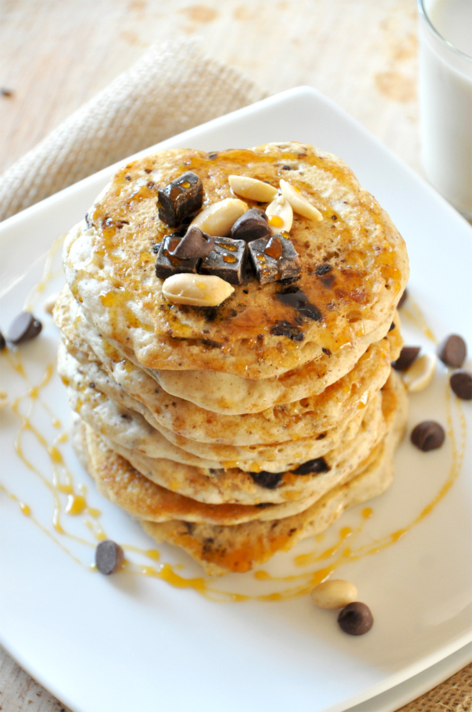 Tall stack of our Vegan Snickers Pancakes recipe topped with peanuts and dark chocolate