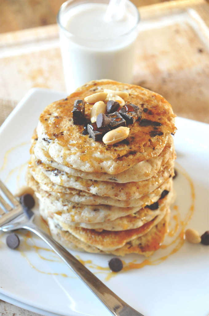 Tall stack of Vegan Snickers Pancakes alongside a glass of almond milk