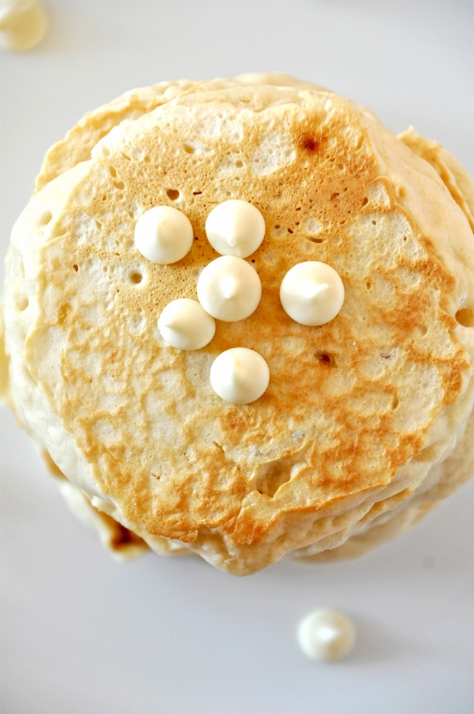 white chocolate cookie pancakes! Tall stack of White Chocolate Macadamia Nut Pancakes topped with extra chocolate chips