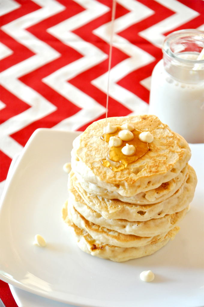 white chocolate macadamia nut cookie pancakes!! Drizzling syrup onto a stack of homemade White Chocolate Macadamia Nut Pancakes