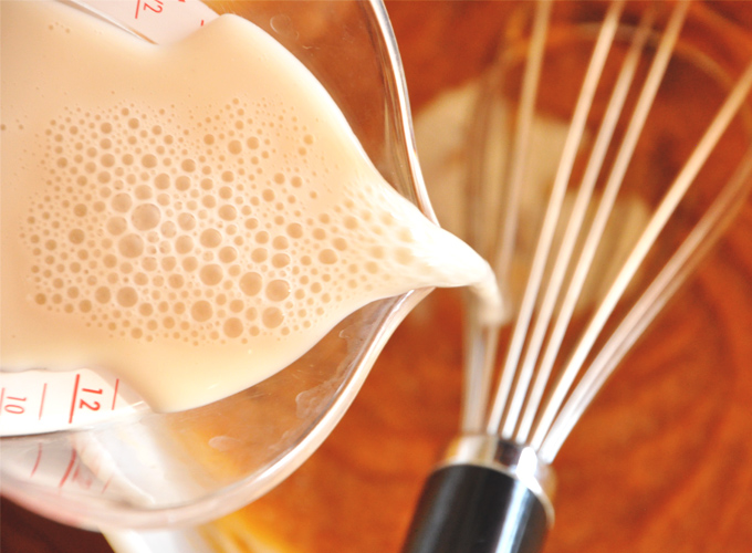 Pouring milk into a bowl for our Vegan Pumpkin Cornbread Waffles batter