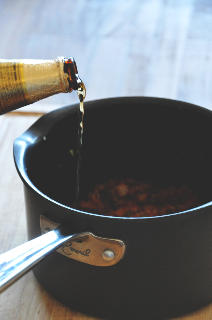 Pouring beer into a large saucepan to make Vegan Beer Chili