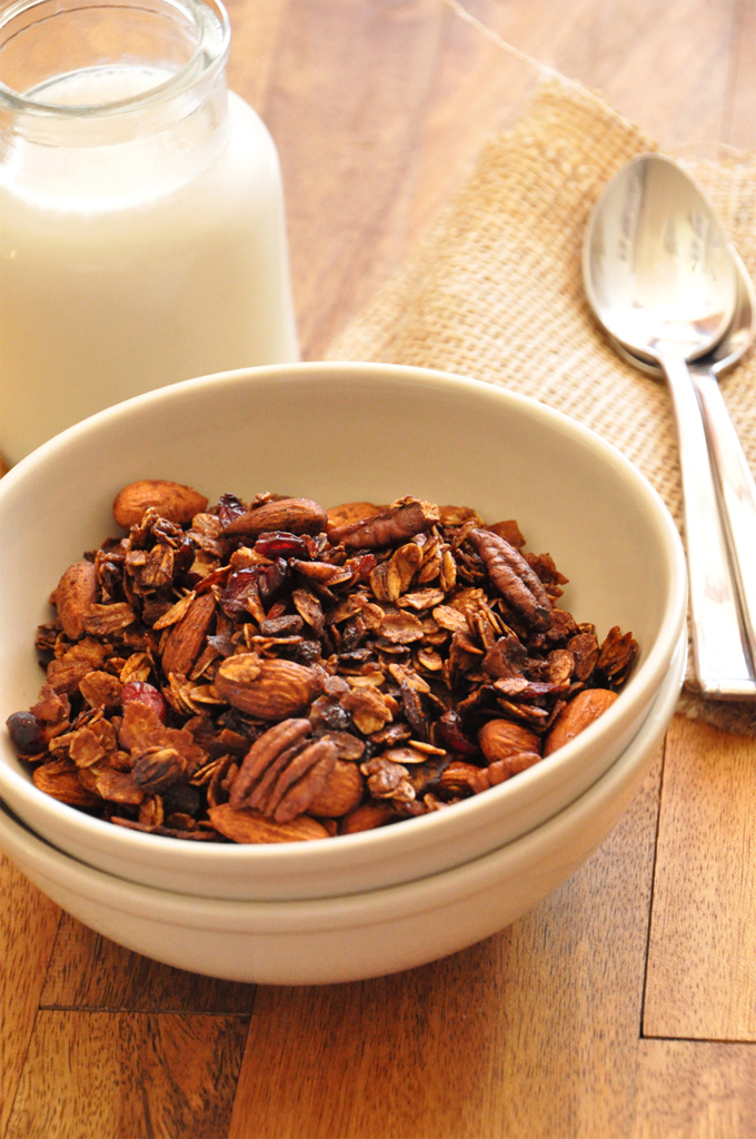 Simple Coconut Granola Bowl of Nut and Honey Coconut Granola alongside a glass of almond milk
