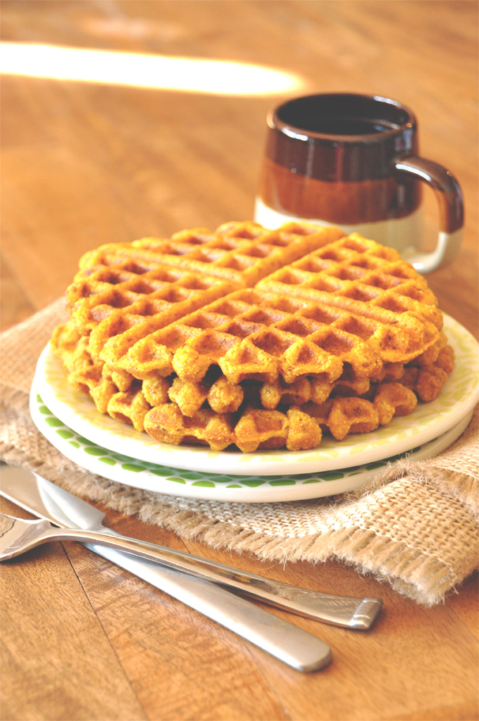 Stack of homemade Vegan Pumpkin Cornbread Waffles alongside a mug of coffee