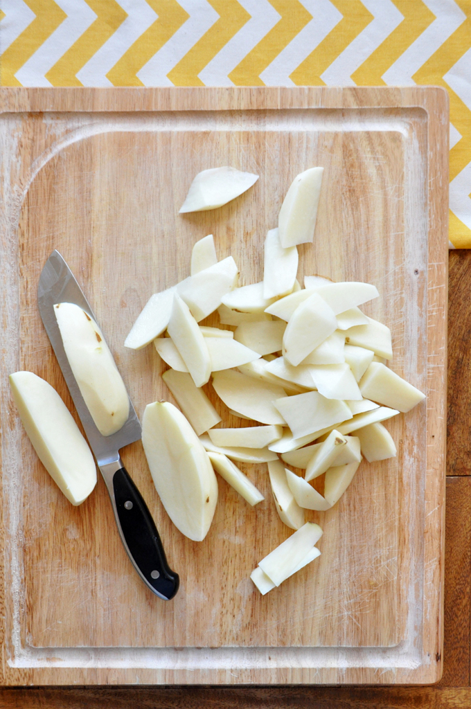 Crispy Fries Cutting board with freshly peeled and chopped potatoes for making our Baked Rosemary Garlic Fries recipe