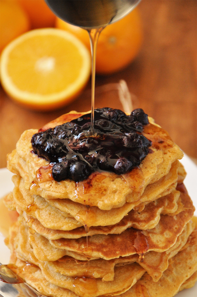 Griddle Cakes with Fresh Orange Blueberry Compote || Minimalist Baker Close up shot of drizzling syrup onto griddle cakes for a delicious breakfast