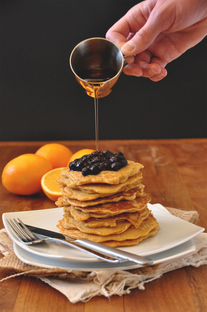 Griddlecakes with Blueberry Orange Compote Pouring syrup onto a giant stack of our Whole Wheat Griddle Cakes recipe