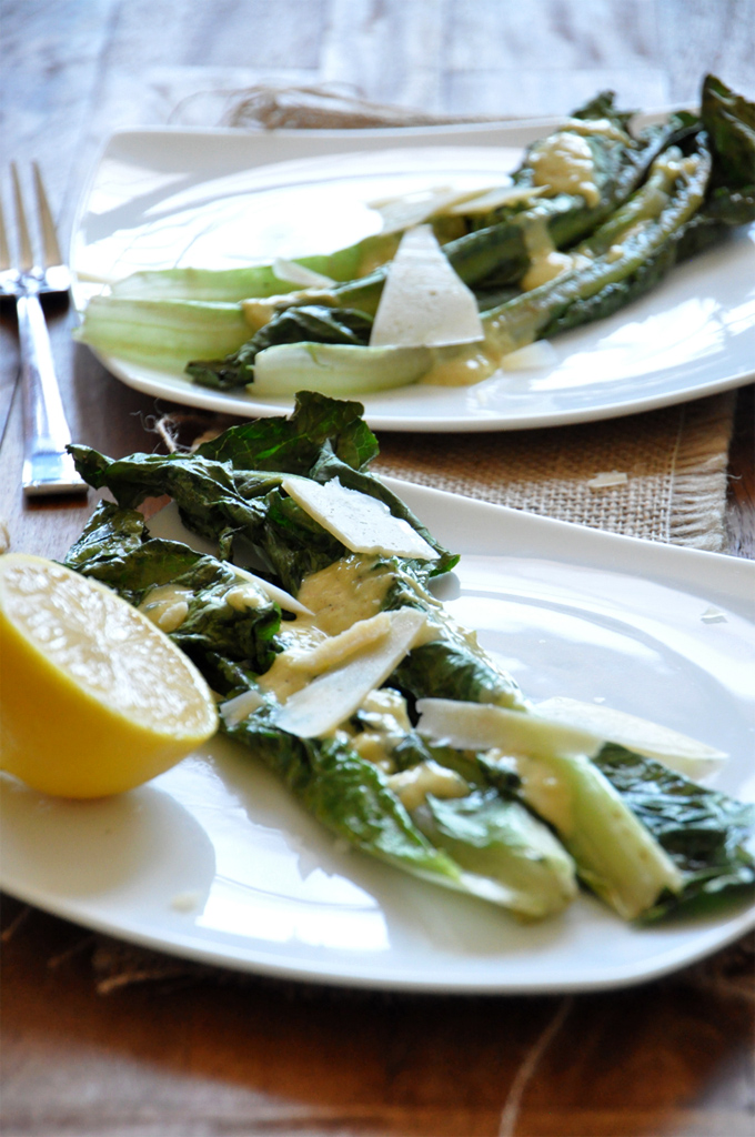 Two plates of Broiled Romaine Salad and a fresh lemon half