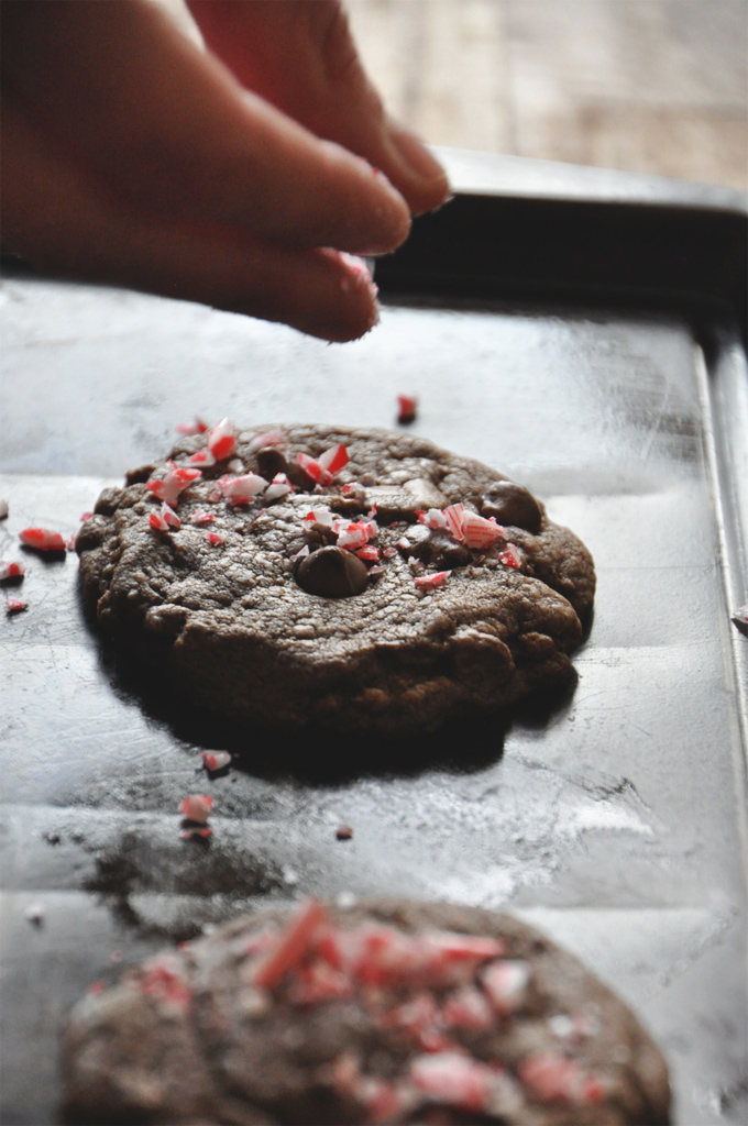 Sprinkling crushed candy cane onto a Chewy Double Chocolate Peppermint Cookie