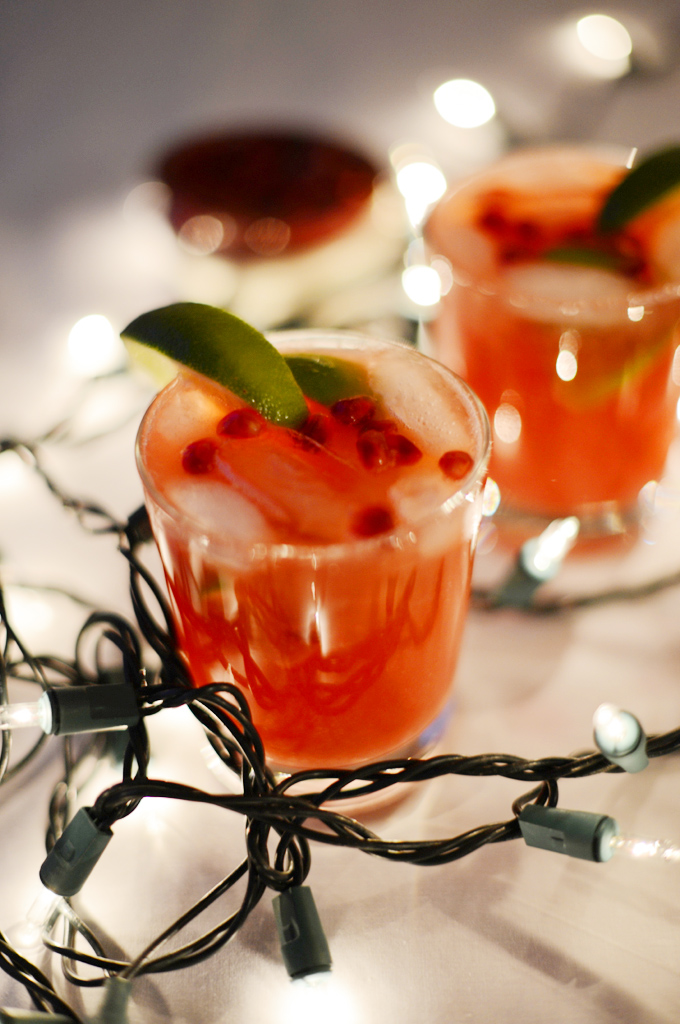 Glasses of Pomegranate Lime Spritzers surrounded by Christmas lights