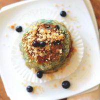 Top down shot of a stack of Vegan Blueberry Muffin Pancakes with fresh blueberries