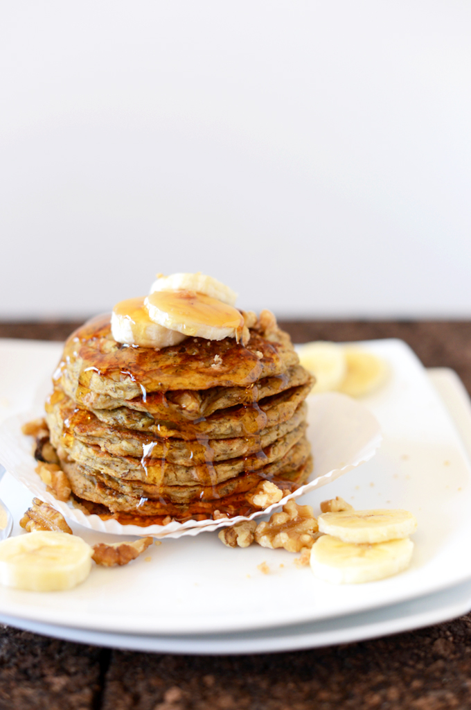 Stack of Banana Nut Muffin Pancakes topped with sliced bananas and syrup