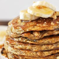 Stack of Vegan Banana Nut Muffins topped with sliced banana and syrup