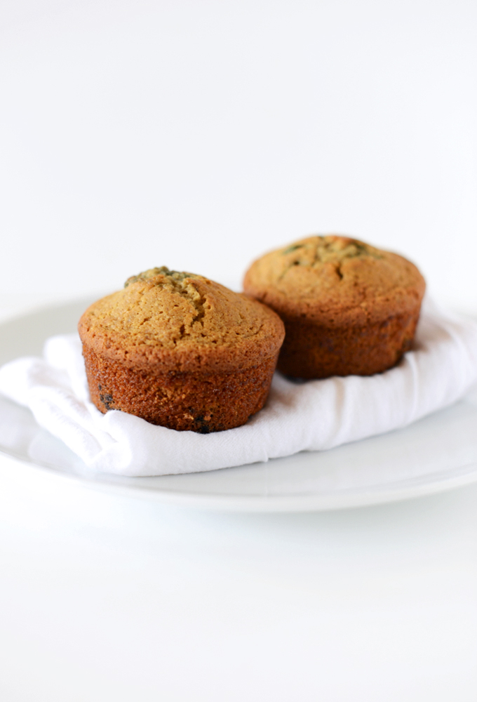 Plate topped with a kitchen towel and two of our simple homemade gluten-free Blueberry Muffins