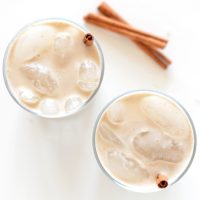 Top down shot of two glasses of Date-Sweetened Horchata with cinnamon sticks as straws