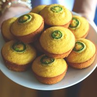 Holding a plate piled high with Gluten-Free Jalapeno Cornbread Muffins
