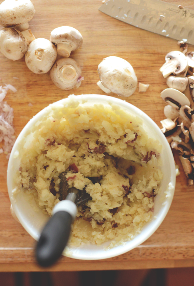 Bowl of cauliflower mashed potatoes surrounded by fresh mushrooms
