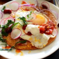 Plate of Gluten-Free Breakfast Tostadas made with kale, radish, egg, and salsa