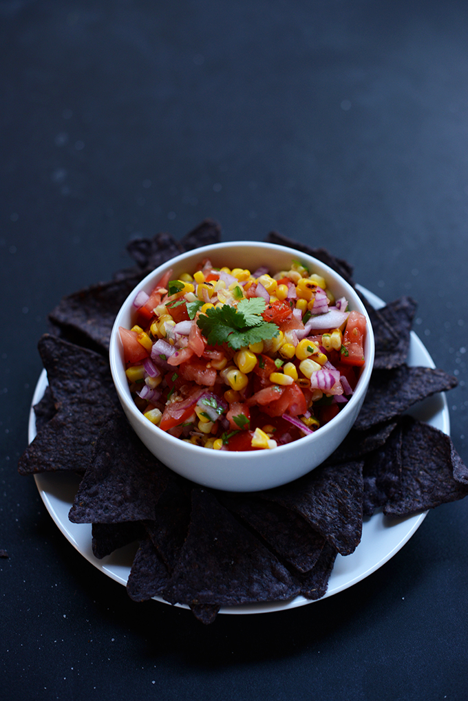 Blue corn tortilla chips surrounded a bowl of homemade Grilled Corn Salsa
