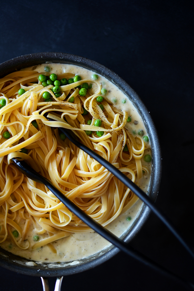 Tongs in a pot of Healthy Alfredo Pasta with Peas