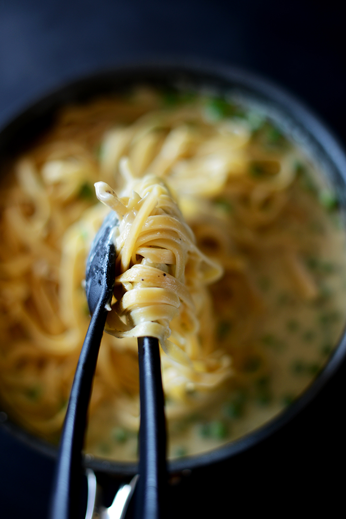 Using tongs to grab some Lightened-Up Alfredo with Peas