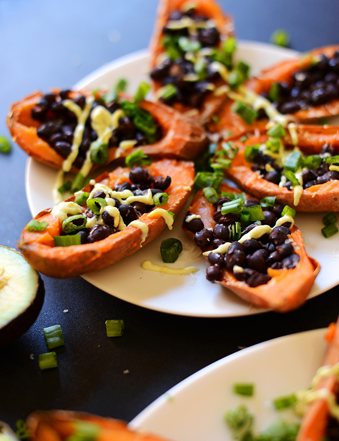 Close up shot of Loaded Black Bean Sweet Potato Boats with green onion and avocado crema
