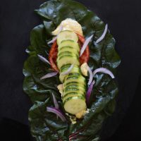Vegan wrap made with a chard leaf, hummus, and fresh vegetables