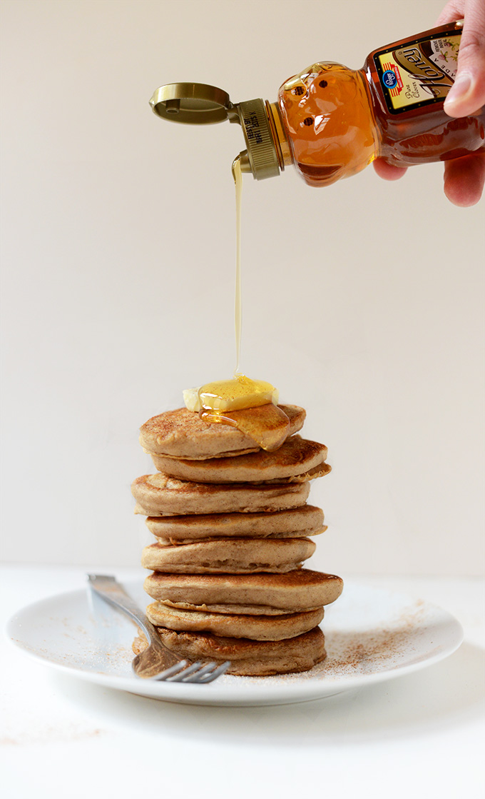 Drizzling honey onto a stack of Mini Sopapilla Pancakes topped with butter