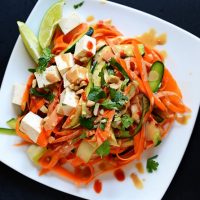 Plate of Noodle-Free Tofu Pad Thai topped with peanut sauce, cilantro, and sriracha
