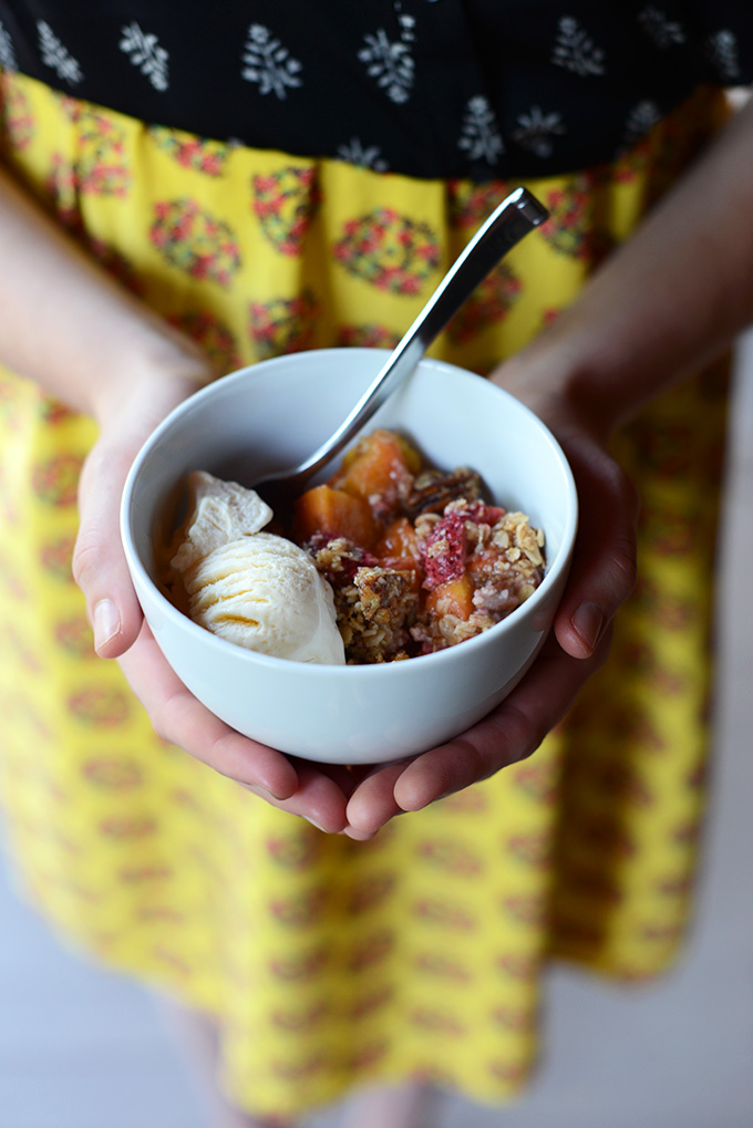 Holding a bowl of gluten-free Strawberry Nectarine Crisp