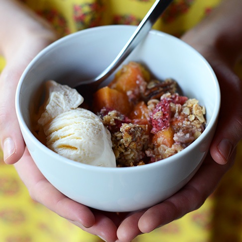 Holding a bowl of Gluten-Free Summer Fruit Crisp with Vegan Ice Cream