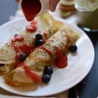 Drizzling strawberry sauce onto Gluten-Free Green Tea Crepes
