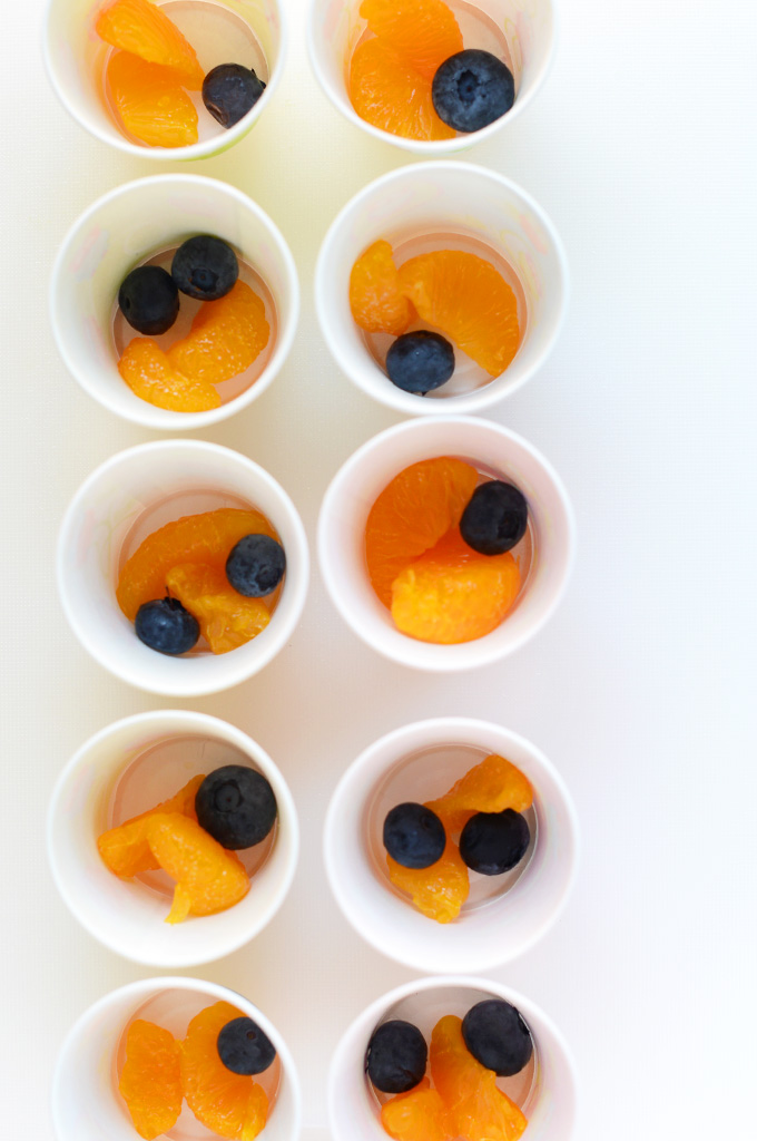Making homemade fruit popsicles in small cups