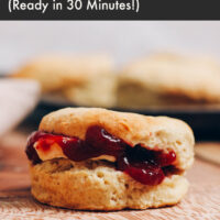 Fluffy vegan biscuit on a cutting board filled with vegan butter and jam