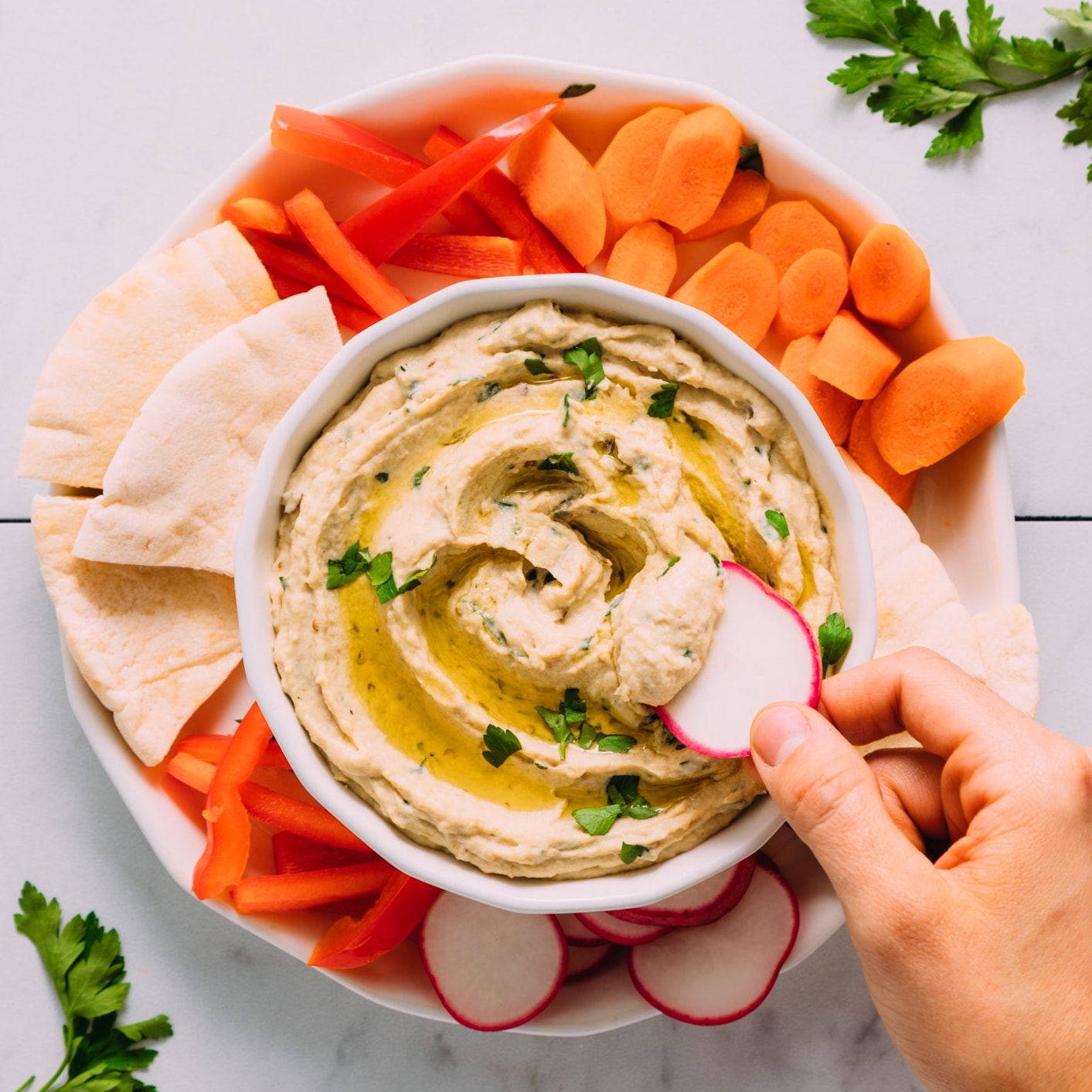 Dipping a radish slice in a bowl of Baba Ganoush
