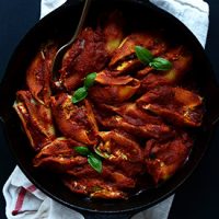 Spoon in a skillet of Dairy-Free Stuffed Shells topped with fresh basil