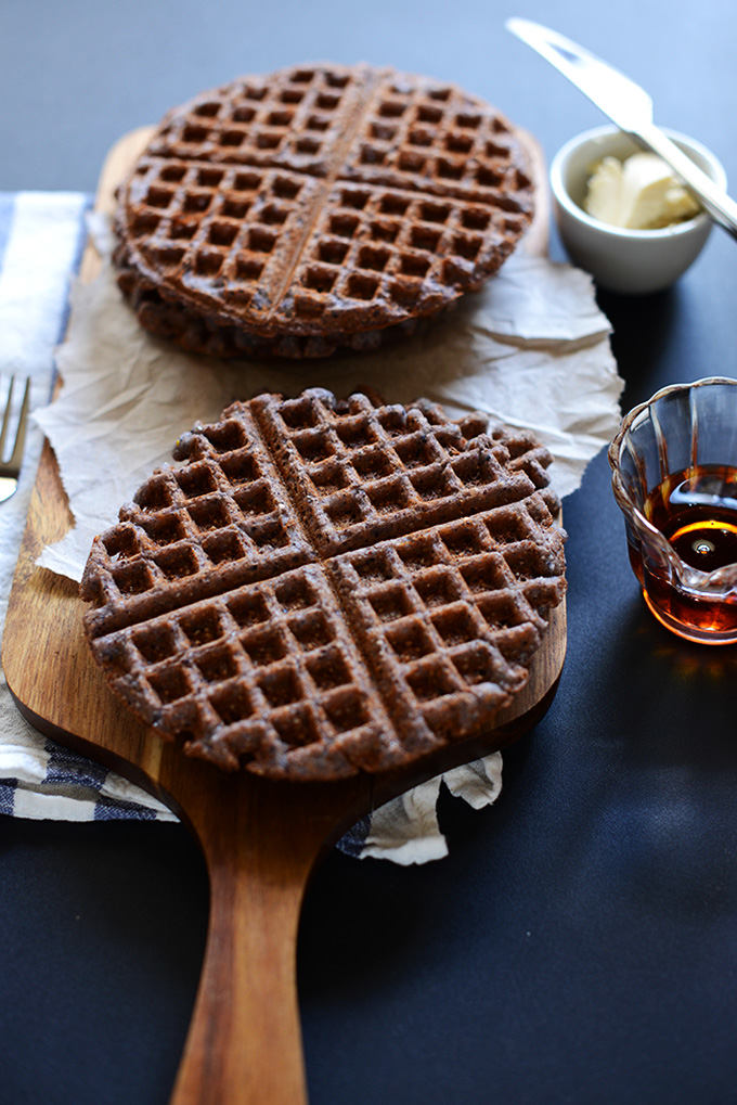 Vegan Gluten-Free Blue Cornmeal Waffles on a cutting board alongside butter and syrup