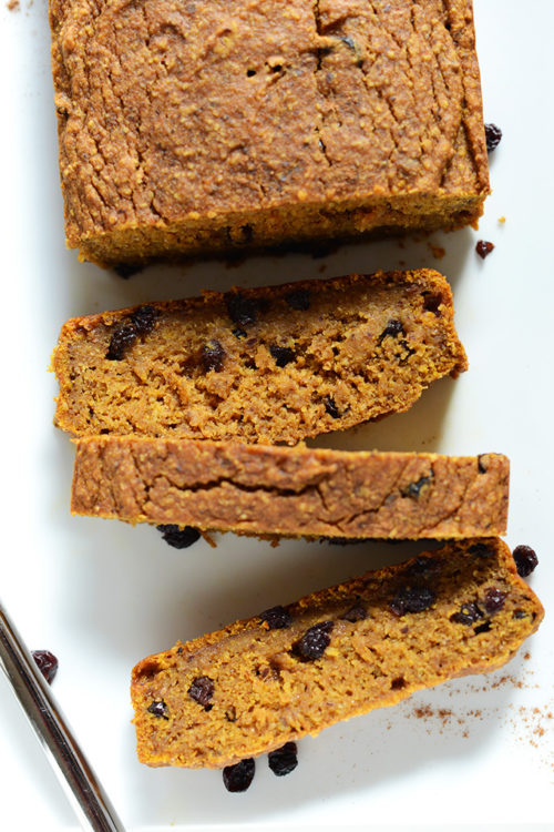 Cascading partially sliced loaf of Easy Vegan Pumpkin Bread with dried currants