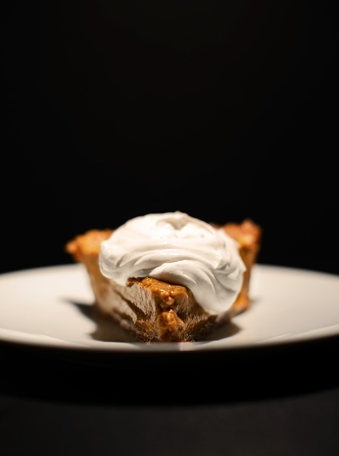 Slice of gluten-free vegan No Bake Pumpkin Pie made with a date pecan crust