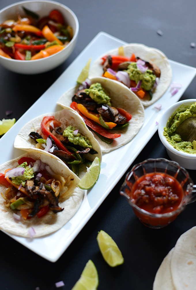 Platter of Poblano and Portobello Vegan Fajitas with bowls of guac, salsa, and peppers