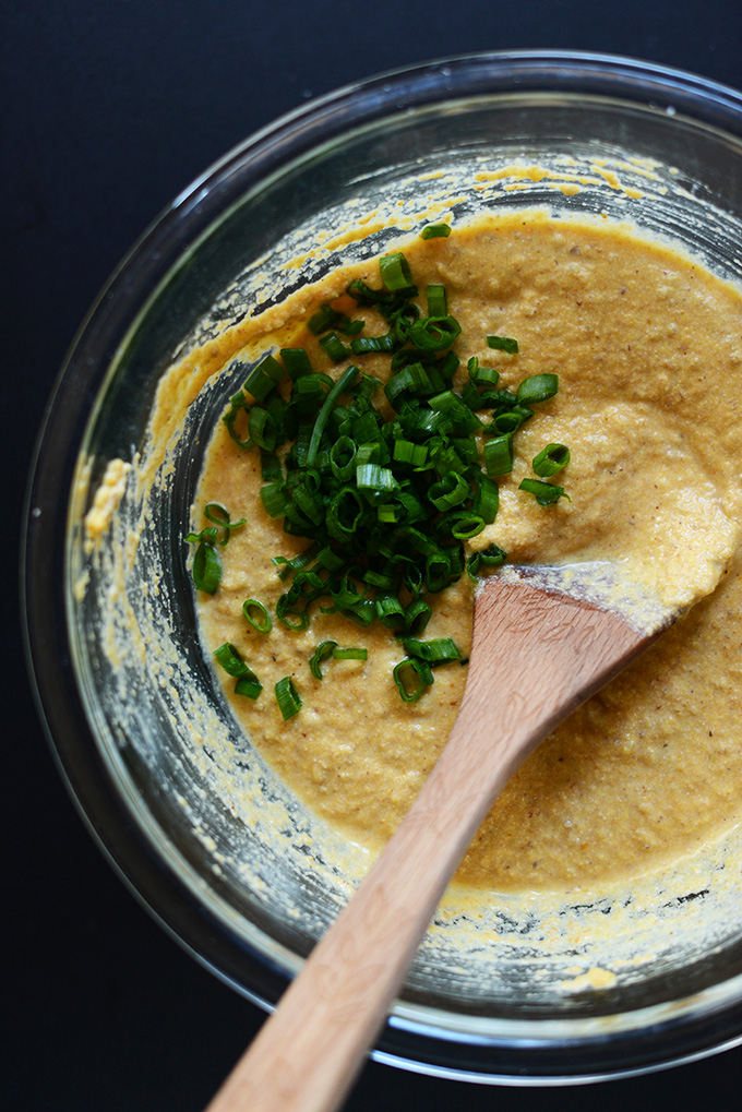 Stirring green onions into Savory Pumpkin Cornbread Waffle batter
