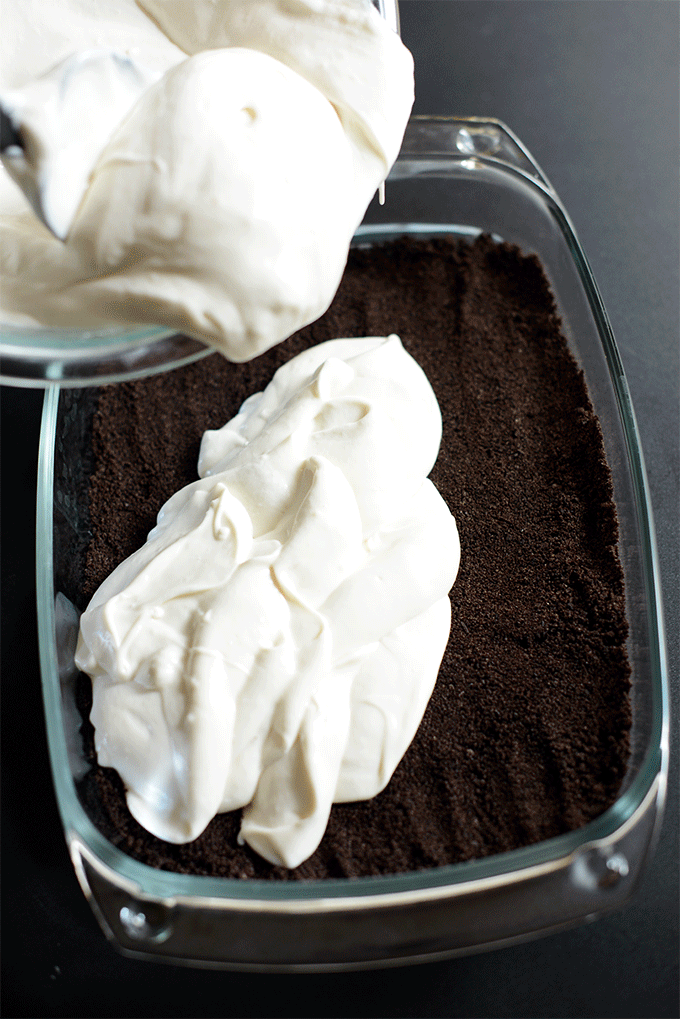 Scooping Vegan Kansas Dirt Cake filling into a baking pan