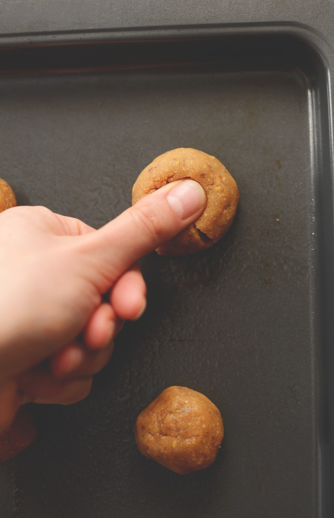 Making a thumbprint in cookie dough balls to make Peanut Butter Jelly Thumbprint Cookies