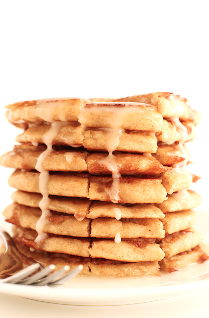 Stack of Fluffy Vegan Cinnamon Roll Pancakes with icing dripping down the side