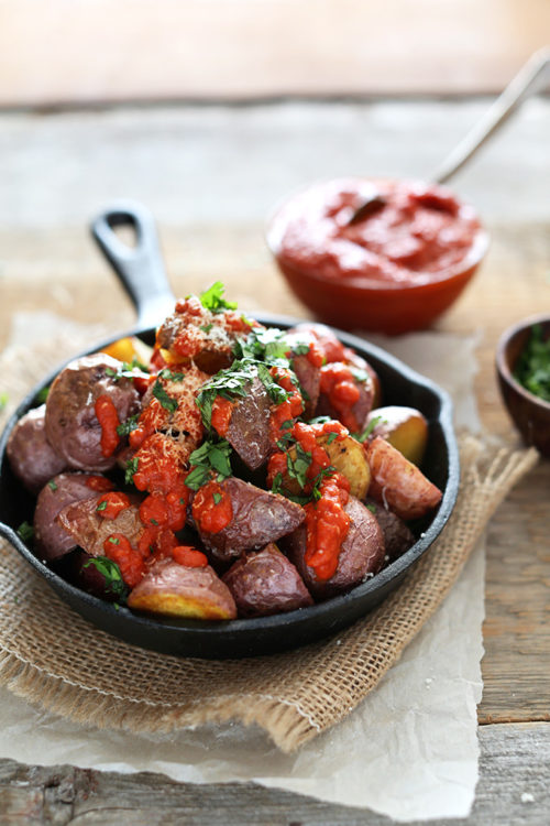 Skillet piled high with Patatas Bravas topped with Spicy Sauce