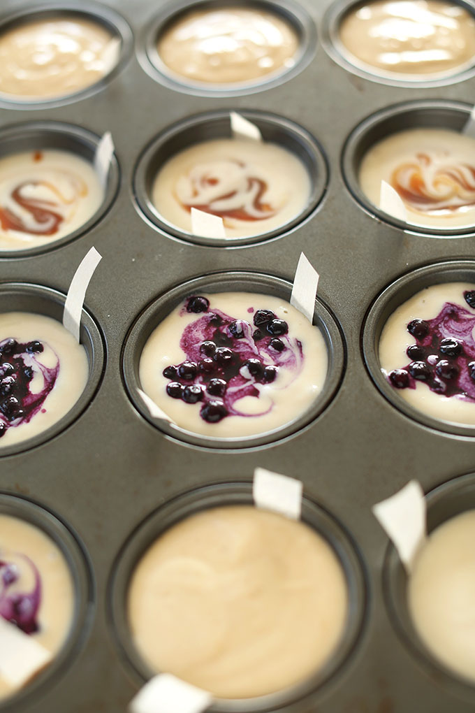 Muffin tin filled with peanut butter, caramel, and blueberry mini Vegan Cheesecakes